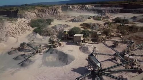 aerial view of a working stone quarry with stone crushers, bulldozers, trucks in a natural environme