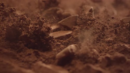 Chocolate Chunks Falling onto Cocoa Powder in Slow Motion