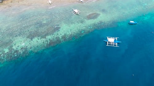 Aerial View of Traditional Filipino Outrigger Boats on Shallow Turquoise Water Near a Sandy Beach