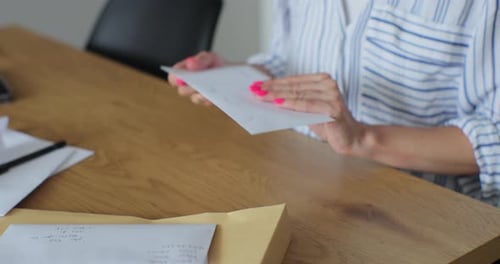 Woman Opens Greeting Card at Desk Indoors