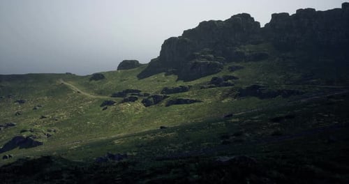 Stunning Hillside with Rocky Terrain and Foggy Distant Mountains