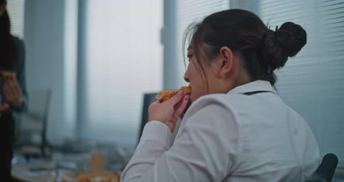 Colleagues Eating Pizza Together During Office Lunch Break