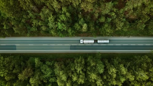 Automobile Driving on Forest Highway Silver Fuel Truck Moving Under Overcast Weather Top View
