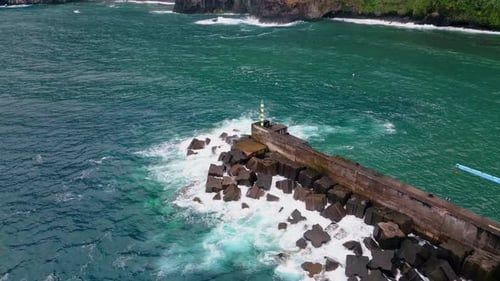Turquoise Sea Splashing Rocks Drone View of Ocean Washing Pier with Lighthouse