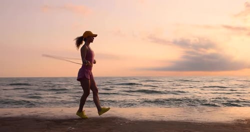 Fit young woman jumping rope at the beach during summer vacation. Slow motion