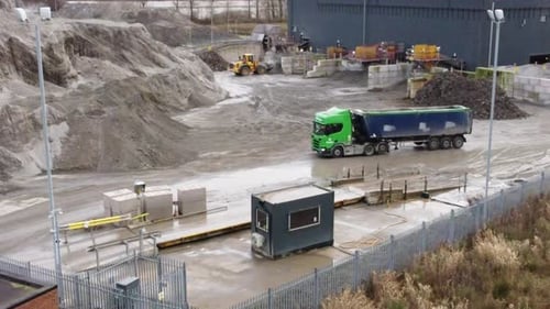 Aerial view, Bulldozer excavator preparing to dump material into loader truck on UK power station co