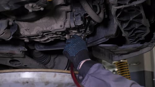A Closeup of the Car Drains Excess Engine Oil in the Car at the Service Station