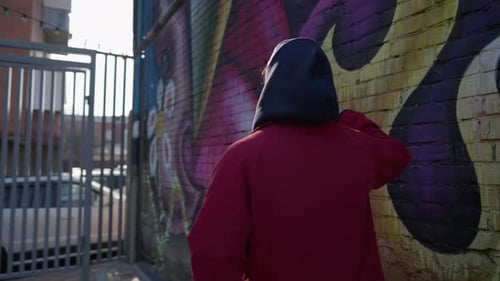 Stilvoller Typ mit Mütze steht auf dem Hintergrund einer mit Graffiti bemalten Wand