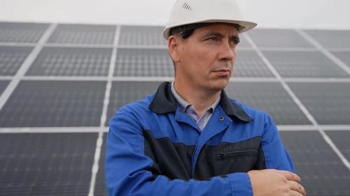 Hombre ingeniero de servicio de pie con los brazos cruzados frente a paneles solares Técnico de mantenimiento