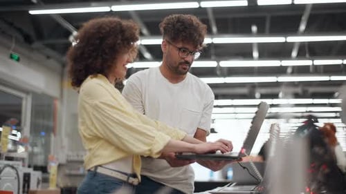 Young couple shopping for new laptop in electronics store