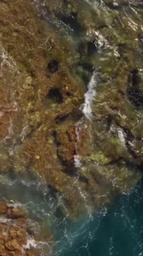Aerial View of Rocky Coastlines in the Canary Islands Capturing Ocean Waves, vertical shot