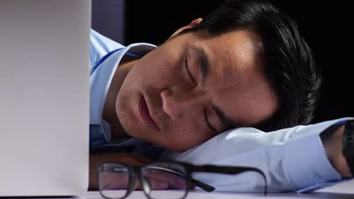 Asian Male Programmer Yawning And Sleeping While Writing Code By A Laptop Using Multiple Monitors