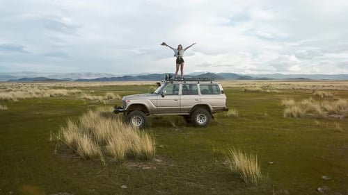 Woman Celebrates Adventure on Car Roof