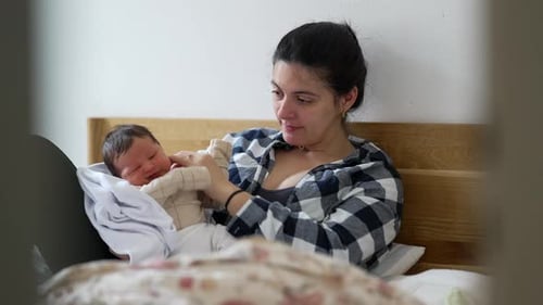 Mother Holds Newborn Infant in Bedroom