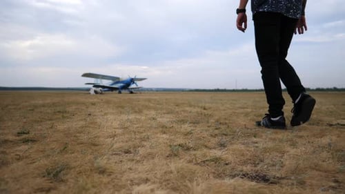 Pilot Approaches Parked Aircraft on Dry Grass Airfield Showcasing the Anticipation of Flight with