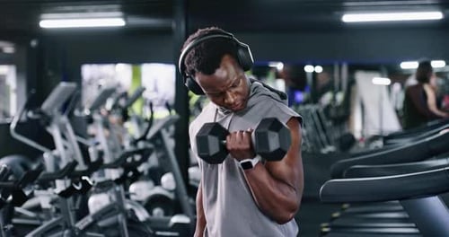 Happy, man and headphones with dumbbell at gym for fitness, streaming podcast and weightlifting