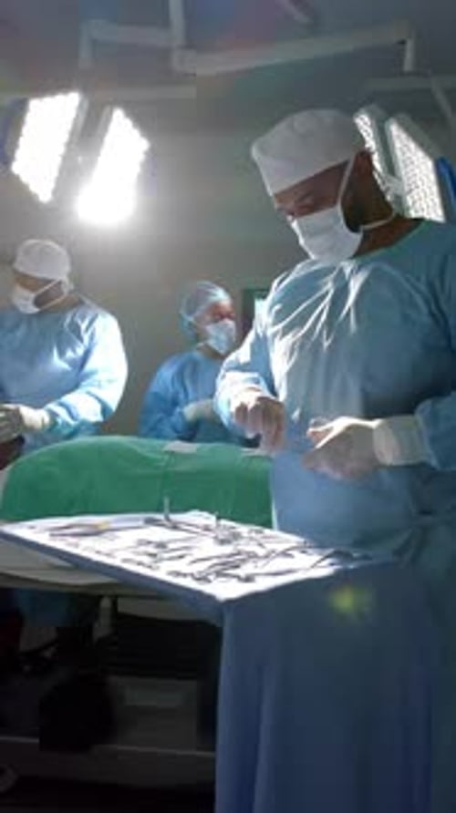 Vertical video of african american male surgeon preparing surgical instruments, slow motion