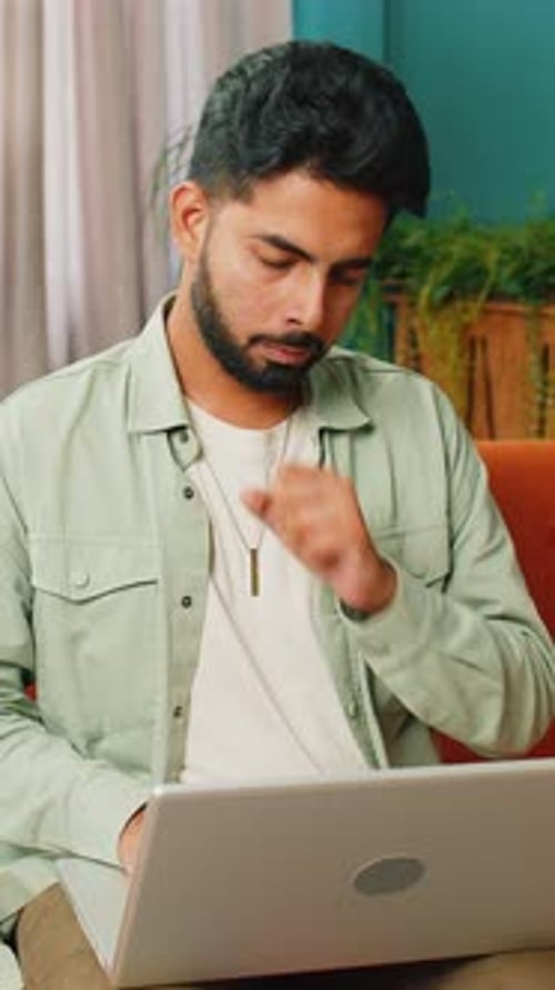 Man on Couch Experiencing Frustration While Using Laptop