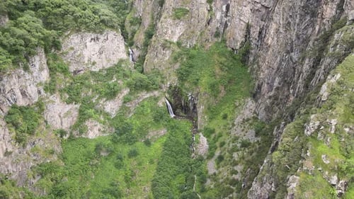 landscape shot of waterfall in the middle of rocky mountains caucasian mountains