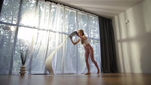 Woman Unfurling Yoga Mat in Bright Studio