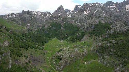 Flying over a mountain village in the Alps against the backdrop of epic beautiful rocks. Aerial view