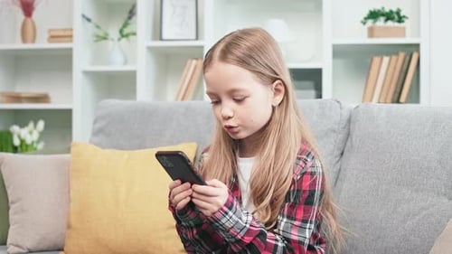 Child Using Smartphone on Couch at Home