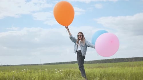 Happy Girl with Big Multicolored Balloons Posing on the Field