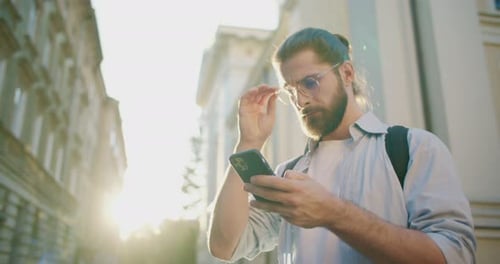 Side View of Attractive Busy Male Tourist Standing Outdoors Texting Chatting and Communicating