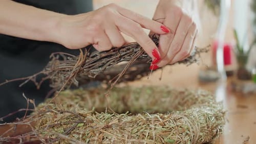 Female Hands Tying Dry Twig Wreath on Straw Base Using Thin Wire
