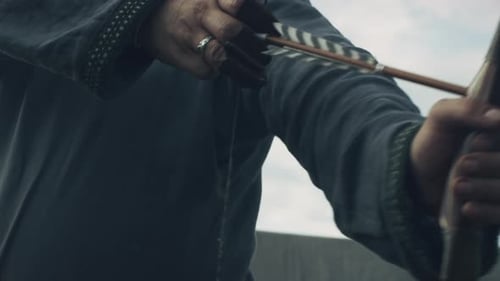 Mittelalterlicher Bogenschütze zieht eine Bogensehne, zielt und bereitet sich auf den Schuss vor. Mittelalterliche Nachstellung.