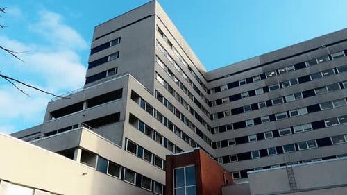 Establishing Shot Panning Up Hospital Building Entrance Over Blue Sky