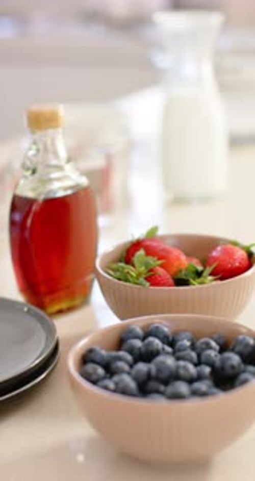 Vertical video: Soft light nudging camera, moving on counter, showing pink bowls and syrup bottle