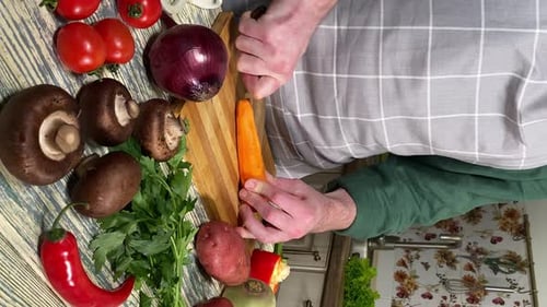 Adult Chopping Carrots on Cutting Board in Kitchen