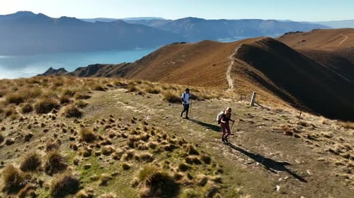 Couple Nordic walking on mountain ridge in New Zealand on sunny day, aerial