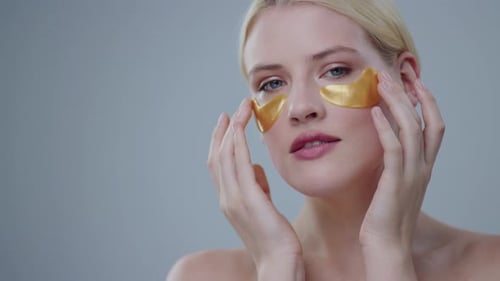 Woman Applying Golden Eye Masks for Beauty Treatment