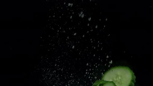 Tranches de concombre tombant dans l'eau.