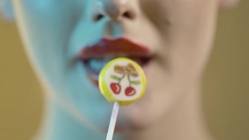 woman licking popsicle, licking lipstick lips, mouth close-up shot on yellow background