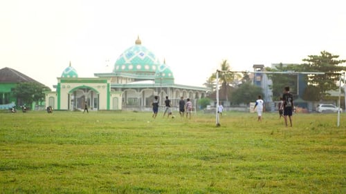Youth Play Soccer by Mosque on Bright Day