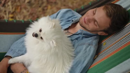 Young Adult Relaxing in Hammock with Dog