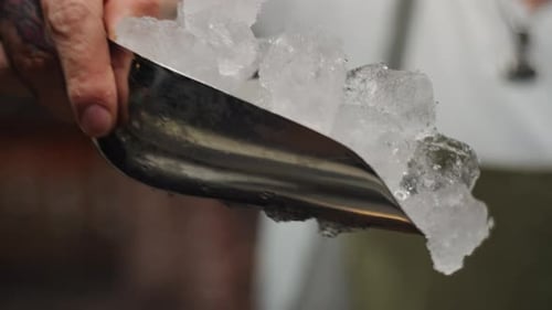 El camarero arroja hielo a la coctelera