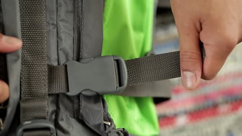 Plan rapproché de mains humaines fermant la boucle du sac à dos