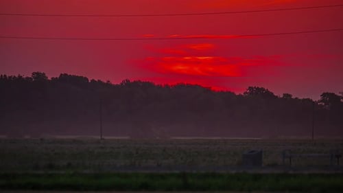 Blick auf die gelbe Sonne, die am frühen Morgen im Zeitraffer über dem roten Himmel aufgeht.