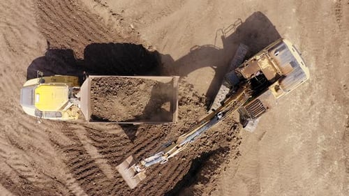 Excavator loading soil onto a Truck, Aerial view.