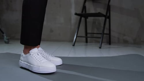 White sportive casual sneakers on male feet. Close up.