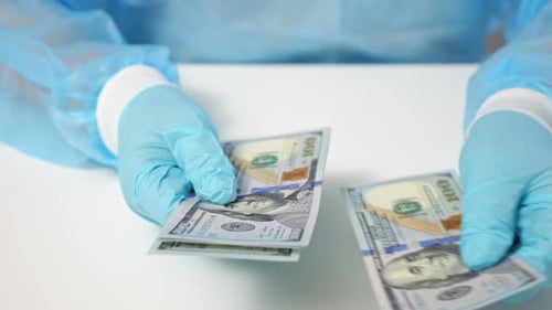 Gloved hands counting hundred dollar bills