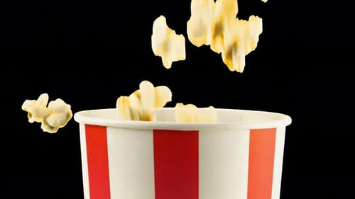 Popcorn grains falling into red and white striped bucket. Slow motion. Alpha channel included