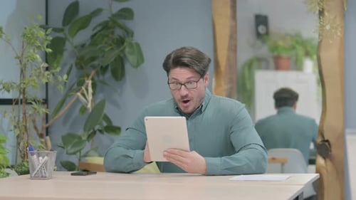 Man Receives Good News on Tablet, Celebrates