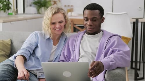 Couple Watches Laptop Together on Couch in Living Room