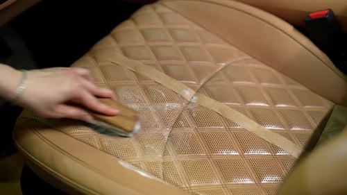 Top View of Dedicated Male Worker Carefully Cleaning Highend Leather Car Seat with Brush and Foam