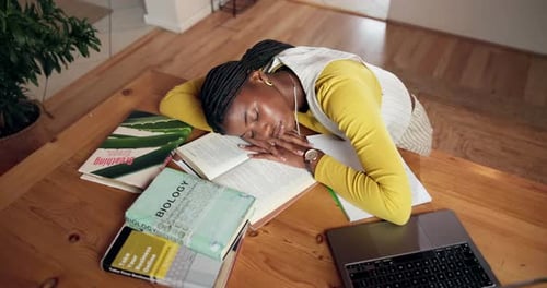 Young Woman Sleeping on Textbooks at Wooden Table